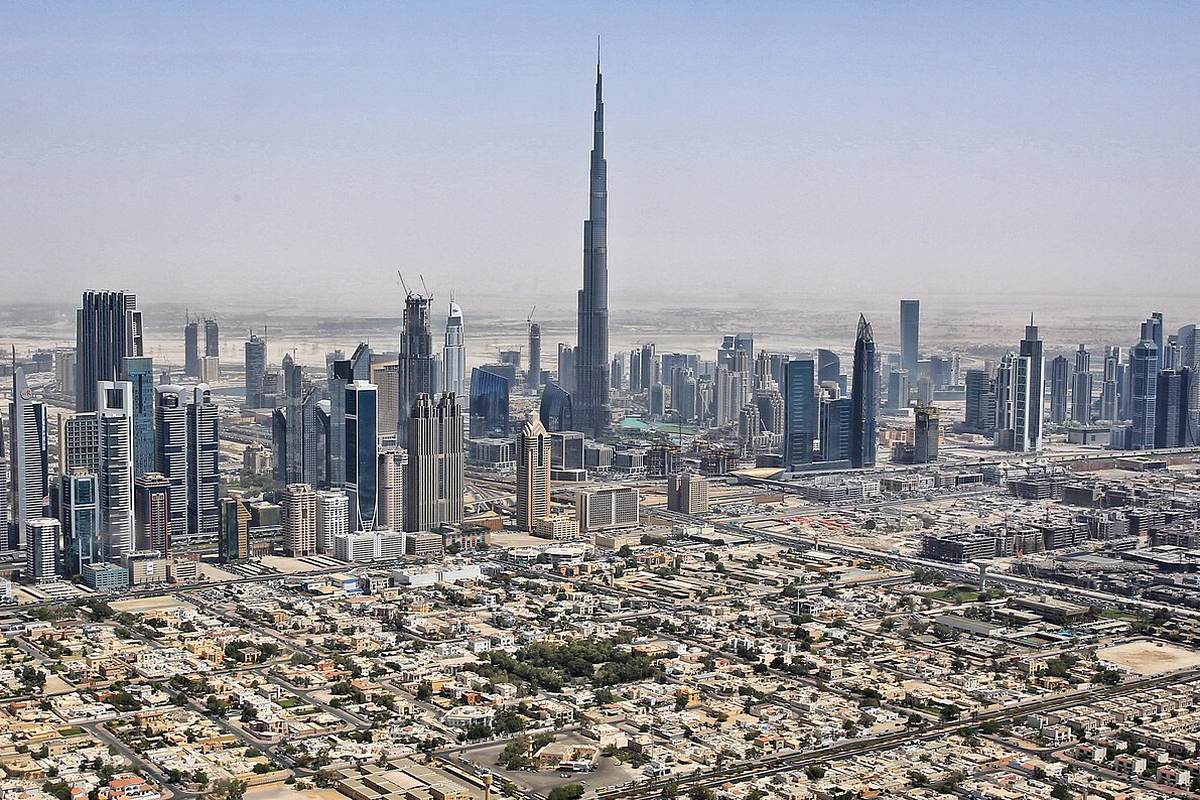 Daylight aerial view of Downtown Dubai, the Burj Khalifa rising above the Sheikh Zayed Road towers with low villa districts in the foreground