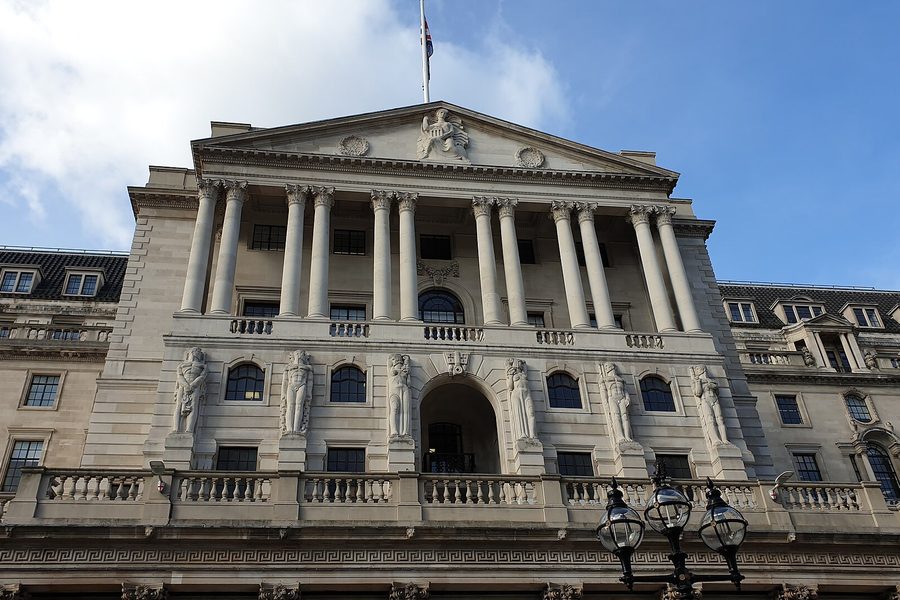 The colonnaded stone facade of the Bank of England in London, its pediment and statues seen from the street below