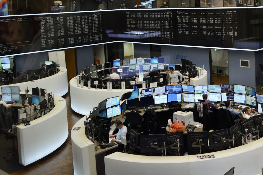 The trading floor of the Frankfurt Stock Exchange, curved white trading pods packed with flat monitors beneath overhead quote boards